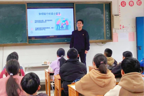 圖為志愿者在崇義縣城關(guān)小學(xué)上綠色環(huán)?？破照n