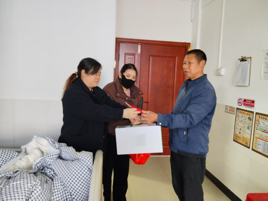 圖為定南縣煙草專賣局駐村隊員黃文平看望患者李紹輝