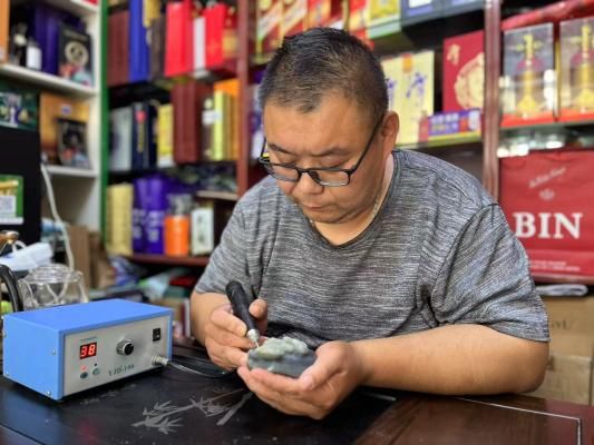 圖為宋濤在玉料上專心雕刻